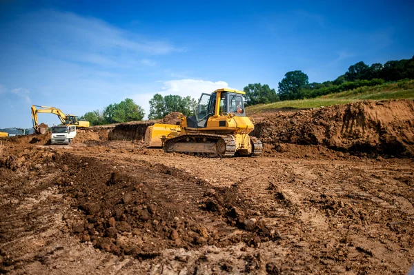 Industrial machinery at working construction building site. Excavator, dumper truck and bulldozer working on ground