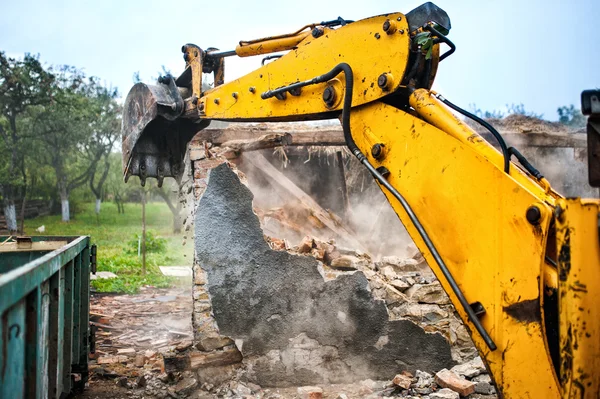 Bulldozer and excavator demolishing concrete brick walls