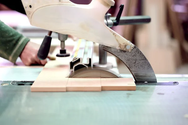 Wood factory worker cutting wood boards with sliding compound mitre saw with sharp blade