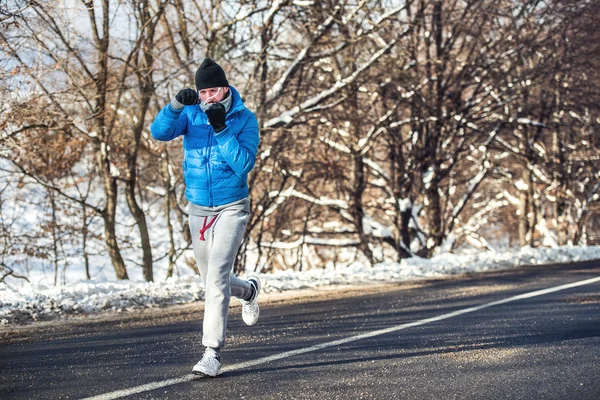 Professional boxer and athlete working out outdoor on snow and cold air.Jogger training for marathon