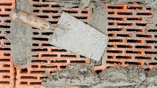 Construction tools close-up, trowel and putty knife with bricks and mortar and cement background