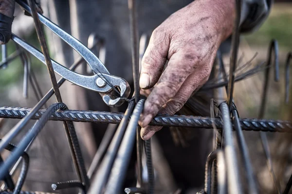 Details of construction worker - hands securing steel bars with wire rod for reinforcement of concrete or cement