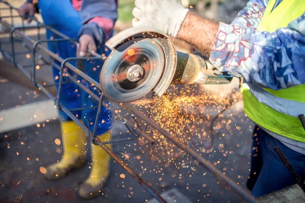 Industrial engineer working on cutting a metal and steel bar with angle grinder, construction site details