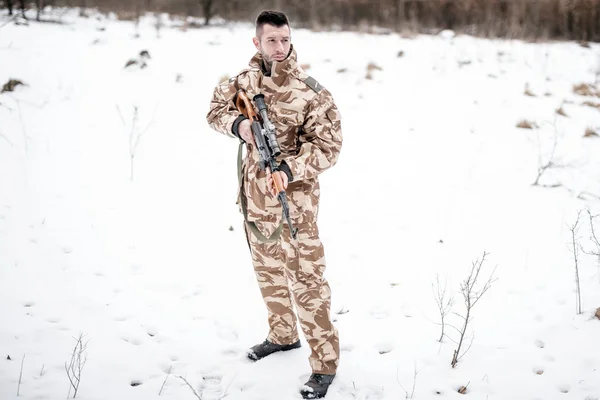 Army ranger with automatic machine gun performing patrol in a snowy forest