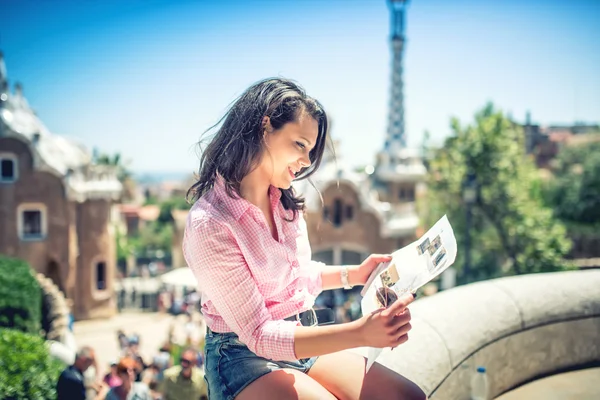 Pretty attractive girl studying map while traveling on a sunny day. Travel concept with beautiful woman on rooftop building with casual, stylish clothes and map