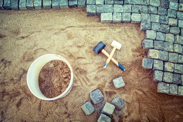 Construction of pavement details, cobblestone pavement, stone blocks and rubber hammers on construction site