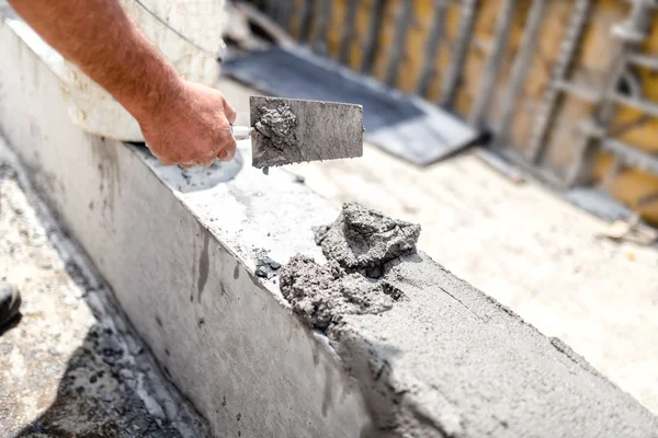 Construction worker leveling concrete with putty knife at building site. Details of construction industry