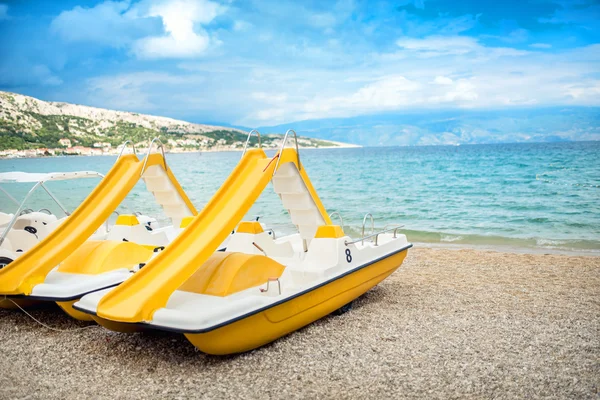 Beach paddle yellow boats, vacation fun details. Rental paddle boats on shore, on beach in exotic resort