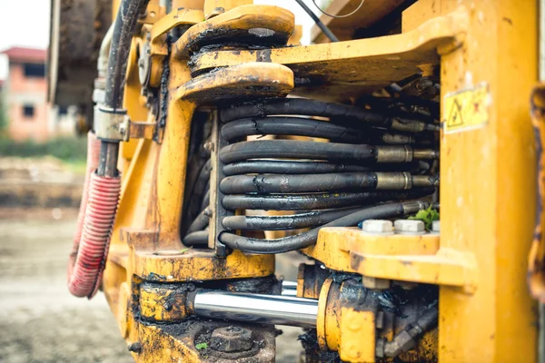 Hidraulic flexible pressure pipes and tubes. Close-up of industrial bulldozer with oil leaks