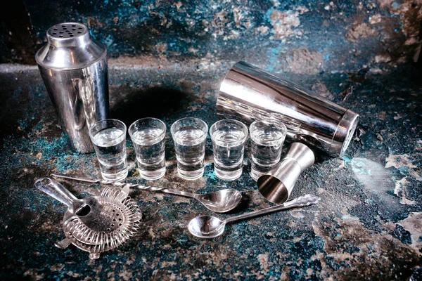 Bartending tools with cocktail shaker, shot glasses and alcoholic drinks. Bar details, nightlife glass alcoholic shots