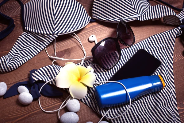 Things on a dark wooden table background. vacation in the south. pebbles, stones. beach accessories. swimsuit, mask and snorkel diving, Sunglasses, sunscreen, phone, headphones. listen to music, relax