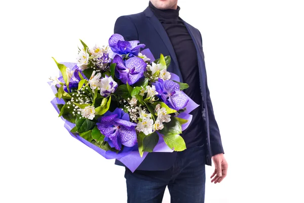 Funny handsome young man with dark suit with a beautiful bouquet in the hands of white and purple flowers isolated on a white background