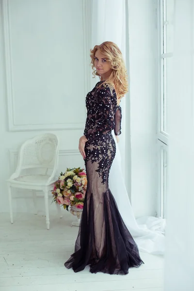 Elegant blonde in evening dress in a light luxury interior