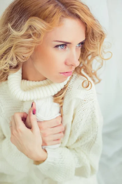 Portrait of a cute girl in warm gentle soft home clothes in bright and stylish interior