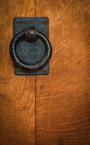 Old black metal circular knocker on oak door