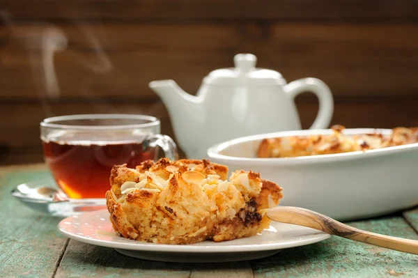 Panettone pudding and steaming hot black tea on shabby wooden ba