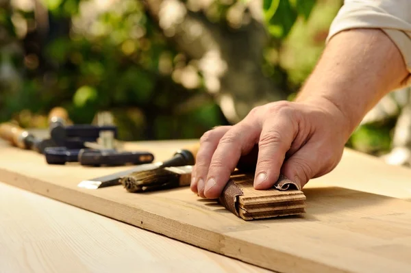 Carpenter hands grinding wooden board