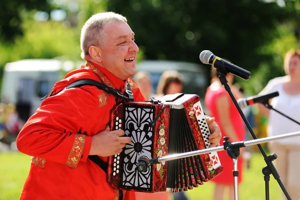 Orel, Russia - July 08, 2016: Russian Valentine Day  - Petr and Fevronia. Senior man in red outfit playing garmoshka, Russian accordion