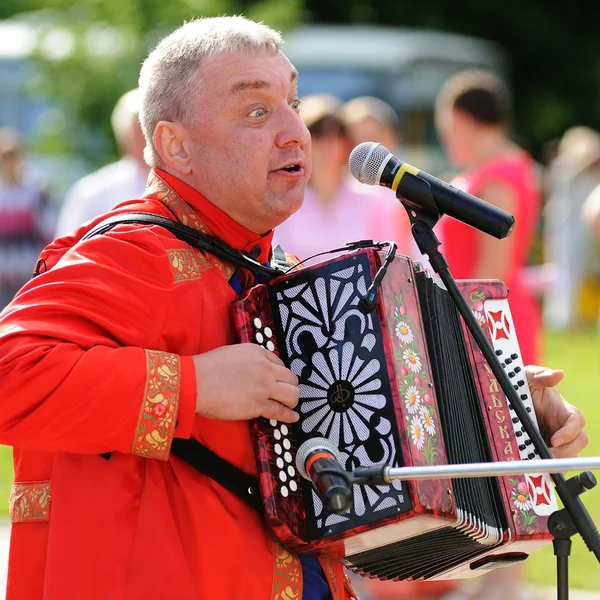 Orel, Russia - July 08, 2016: Russian Valentine Day  - Petr and Fevronia. Senior man in red outfit playing garmoshka, Russian accordion