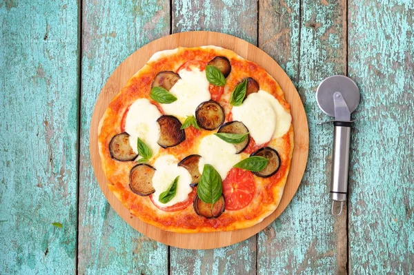 Homemade round pizza with eggplants, tomatoes, basil and mozzarella