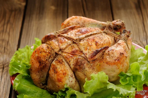 Bondage shibari roasted chicken with salad leaves on red plate o