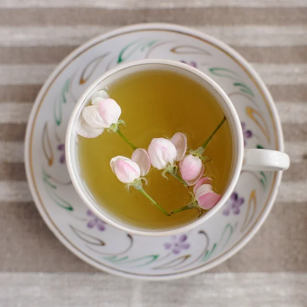 Apple blossom tea in white cup on beige linen