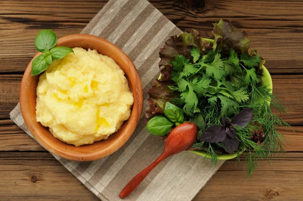 Polenta with basil shoot in wooden bowl with green salad and woo