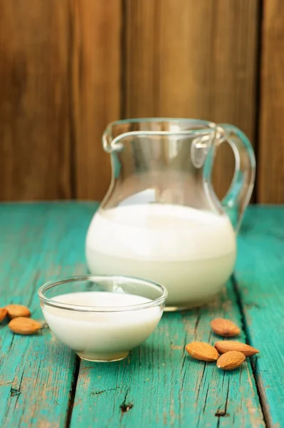 Homemade fresh almond milk in glass jar and glass bowl, with hom