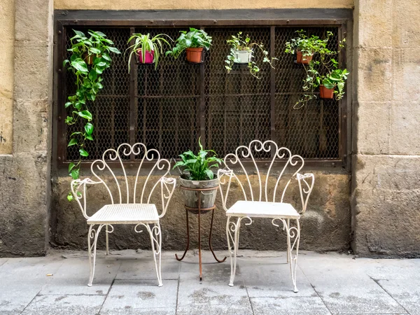 Two white metal chairs in the old town of Barcelona