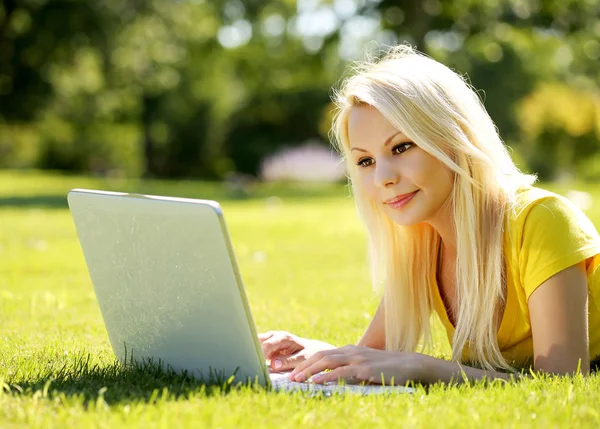 Blonde Girl with Laptop. Smiling Beautiful Woman Lying on Green