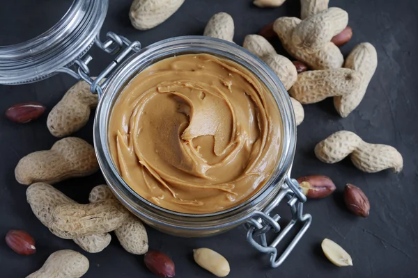 Peanut butter in a glass jar and peanuts