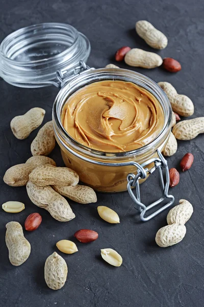 Peanut butter in a glass jar and peanuts