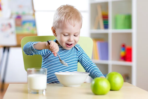 Kid eating healthy food at home or kindergarten