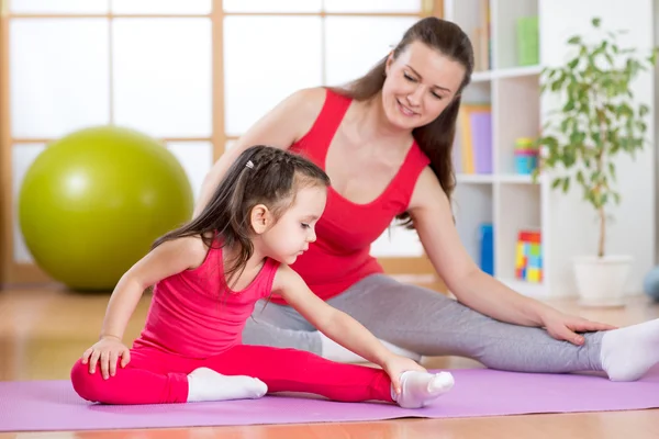 Mother and daughter doing fitness exercises on mat at home