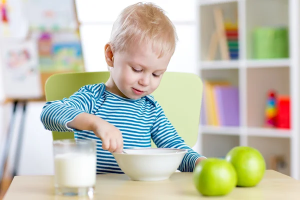 Kid boy eating healthy food at home or kindergarten