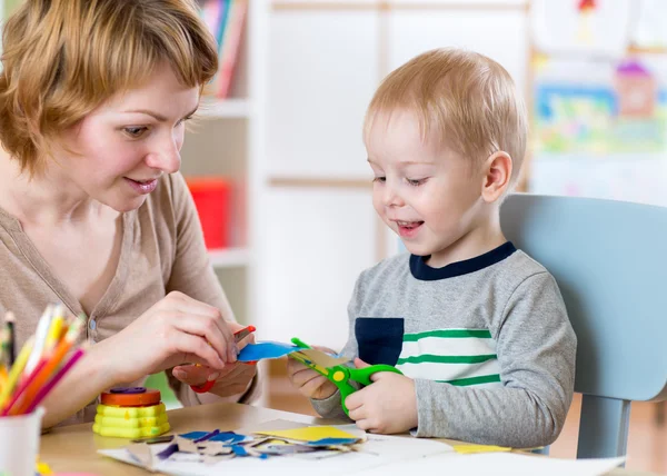 Woman teaches child handcraft at kindergarten or playschool or home