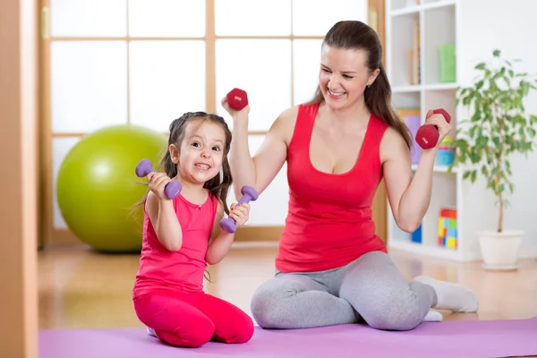 Woman with funny child do exercise lifting dumbbells