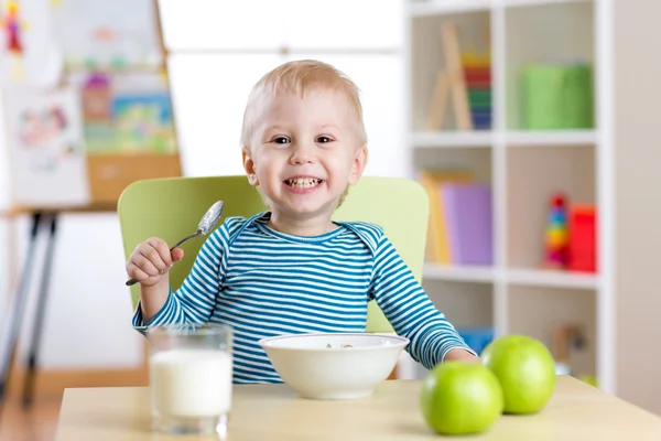 Kid eating healthy food at home or kindergarten