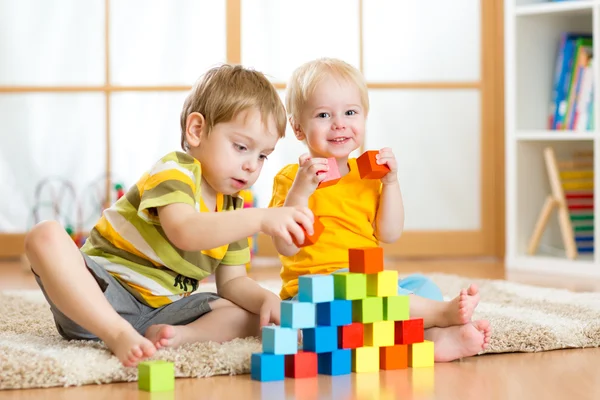 Preschooler children playing with colorful toy blocks. Kid playing with educational wooden toys at kindergarten or day care center. Toddler in nursery.