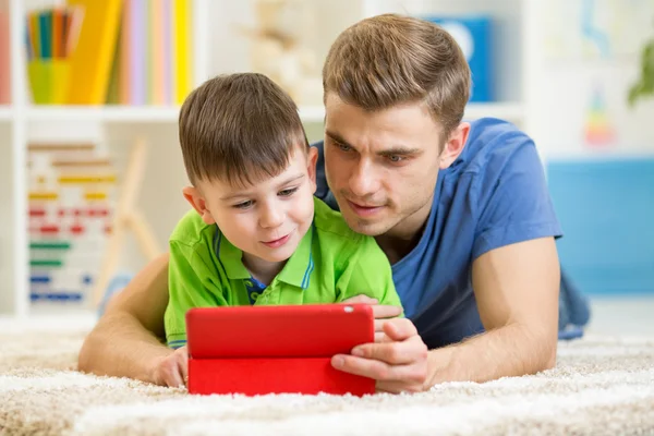Father and son kid playing with tablet computer at home