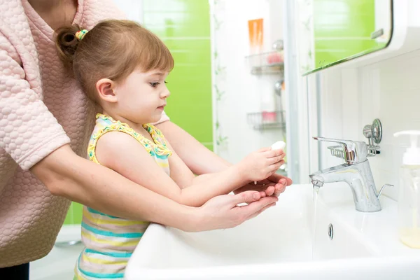 Child girl washing hands with soap in bathroom