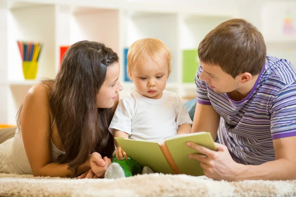 Young parents mom and dad reading children book to baby boy