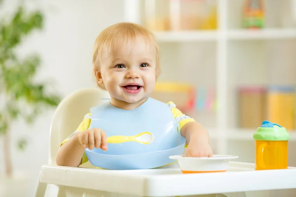 Happy baby kid boy eating food itself with spoon