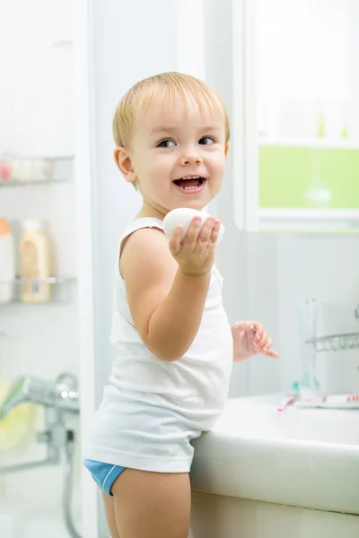 Kid washing hands with soap in bathroom