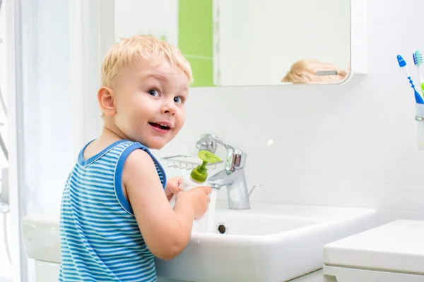 Kid washing his face and hands in bathroom