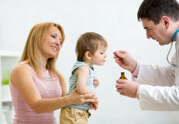 Pediatrician giving spoon dose of medicine drinking syrup to baby