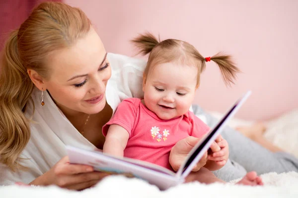 Happy mother read a book to baby girl