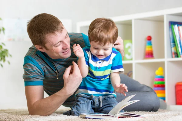 Child boy and dad read a book on floor at home