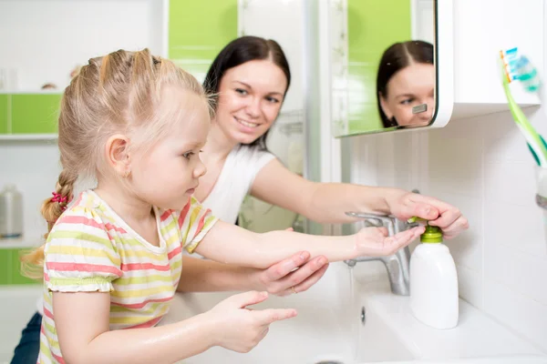 Happy kid with mom washing hands in bathroom