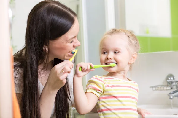 Cute mom teaching child teeth brushing
